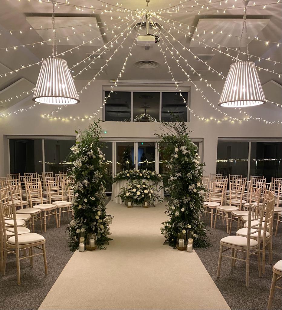a wedding ceremony is taking place in a room with white chairs and flowers