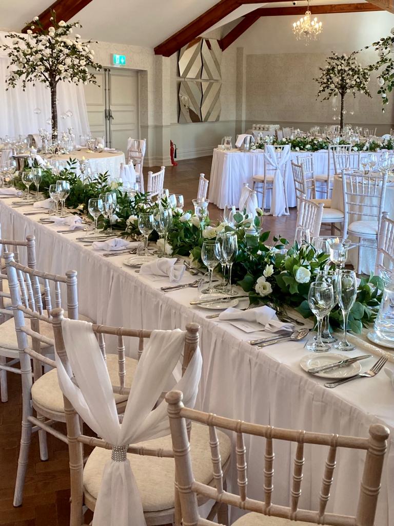 a long table in a room with white tables and chairs