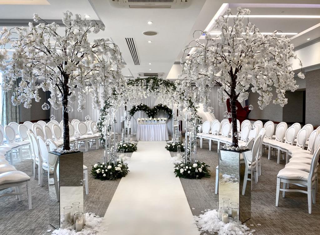 a wedding ceremony is taking place in a room with white chairs and trees