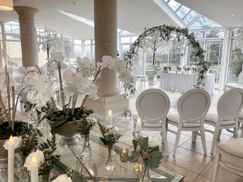 a room with white chairs and a table with flowers and candles