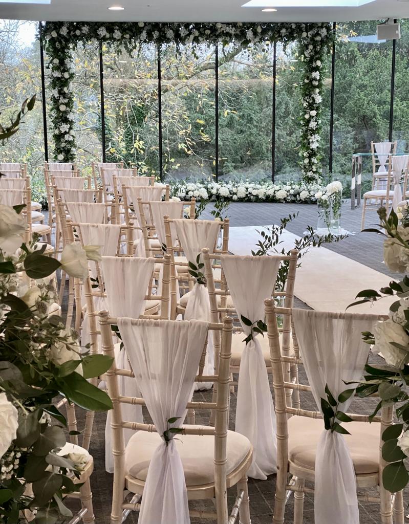 a row of chairs with white flowers on them
