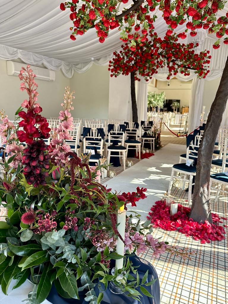 a row of chairs under a canopy with red flowers