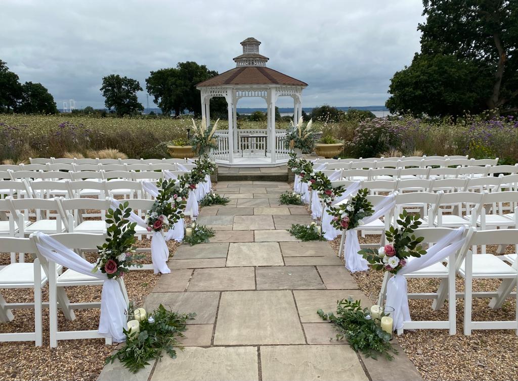 rows of white chairs are lined up in front of a white gazebo