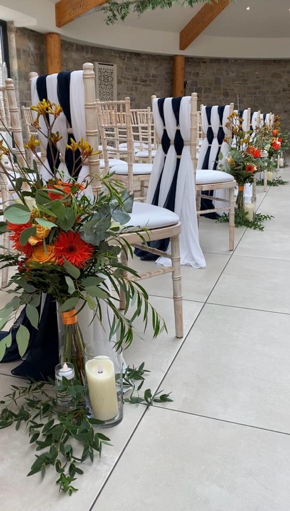 a row of chairs with flowers and candles on them