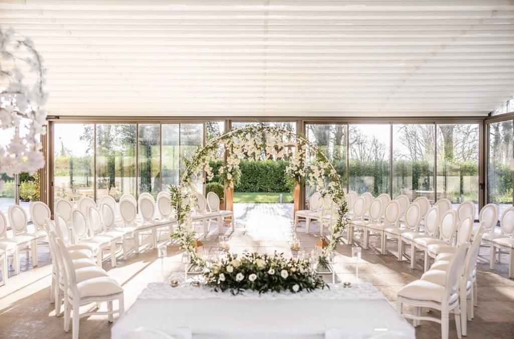 a room filled with white chairs and a floral arch