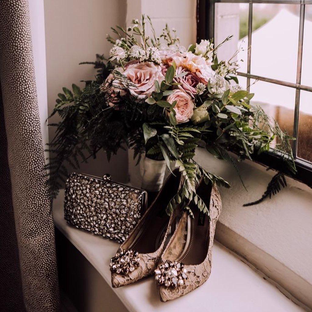 a bouquet of flowers and a pair of shoes are on a window sill