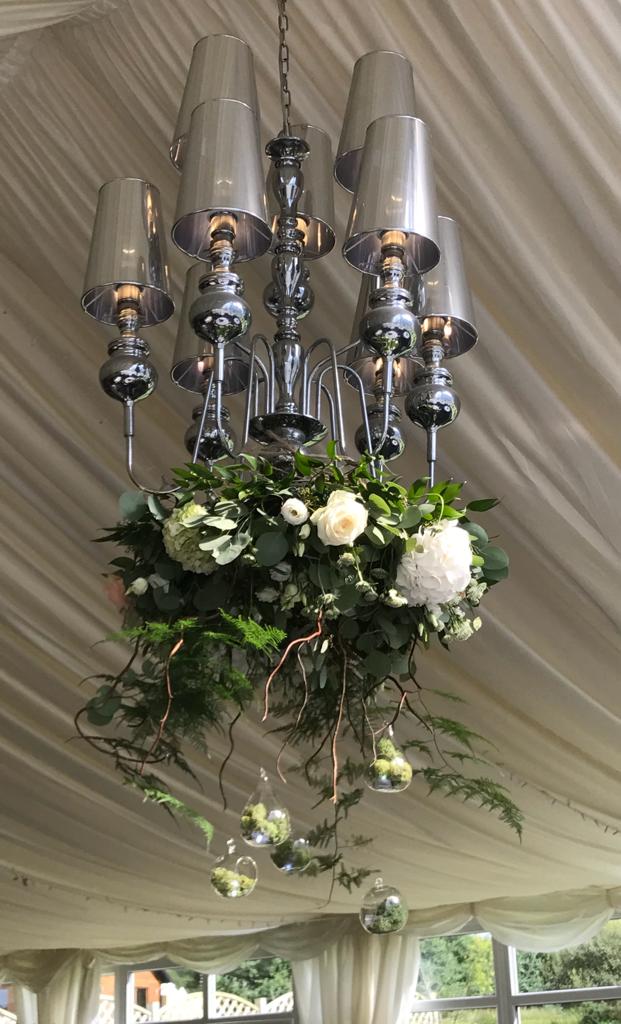 a chandelier is decorated with flowers and greenery