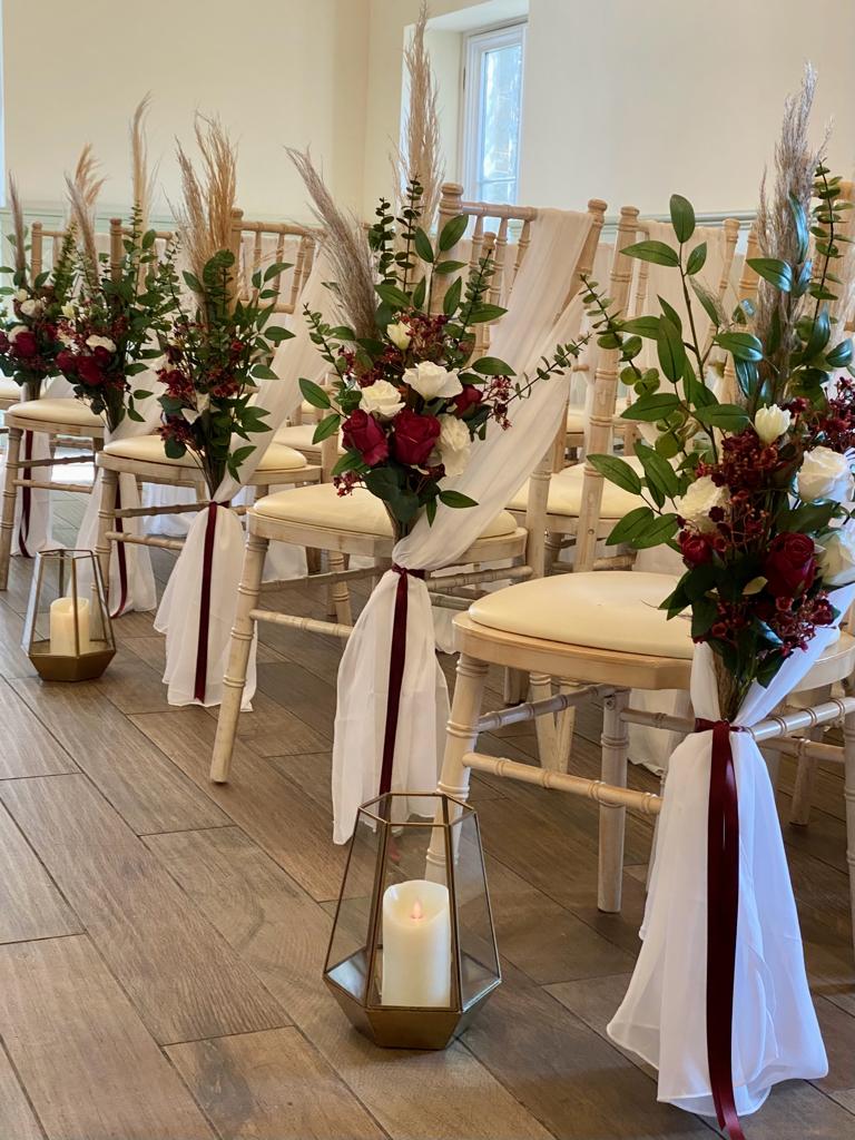 a row of chairs with flowers and candles on them