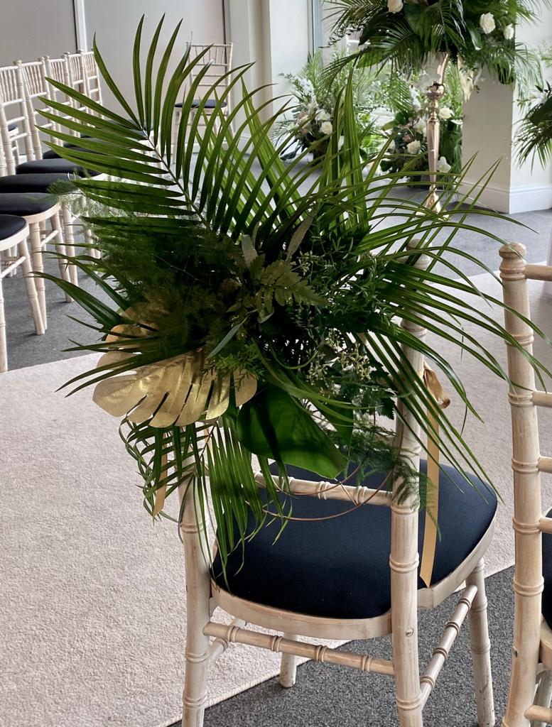 a chair is decorated with tropical leaves and flowers