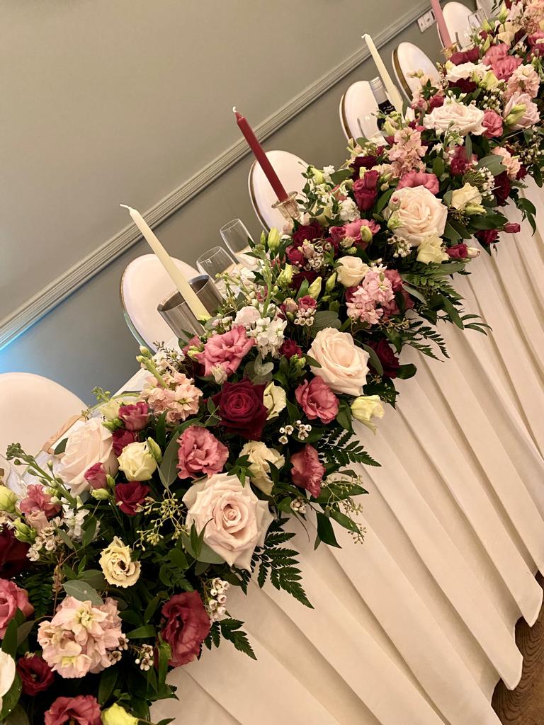 a long white table with flowers and candles on it