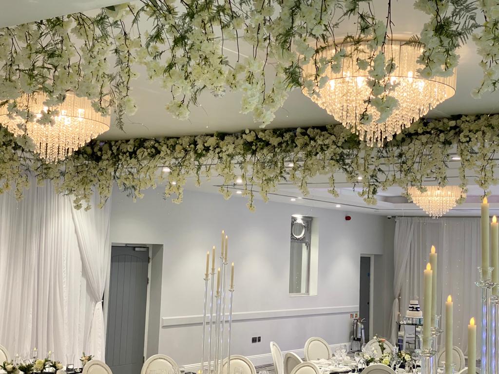 a room with white flowers hanging from the ceiling and chandeliers