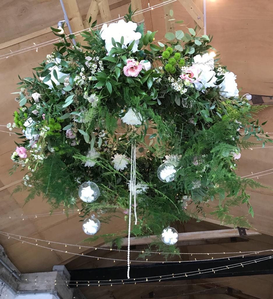 a large wreath of flowers and greenery hangs from the ceiling